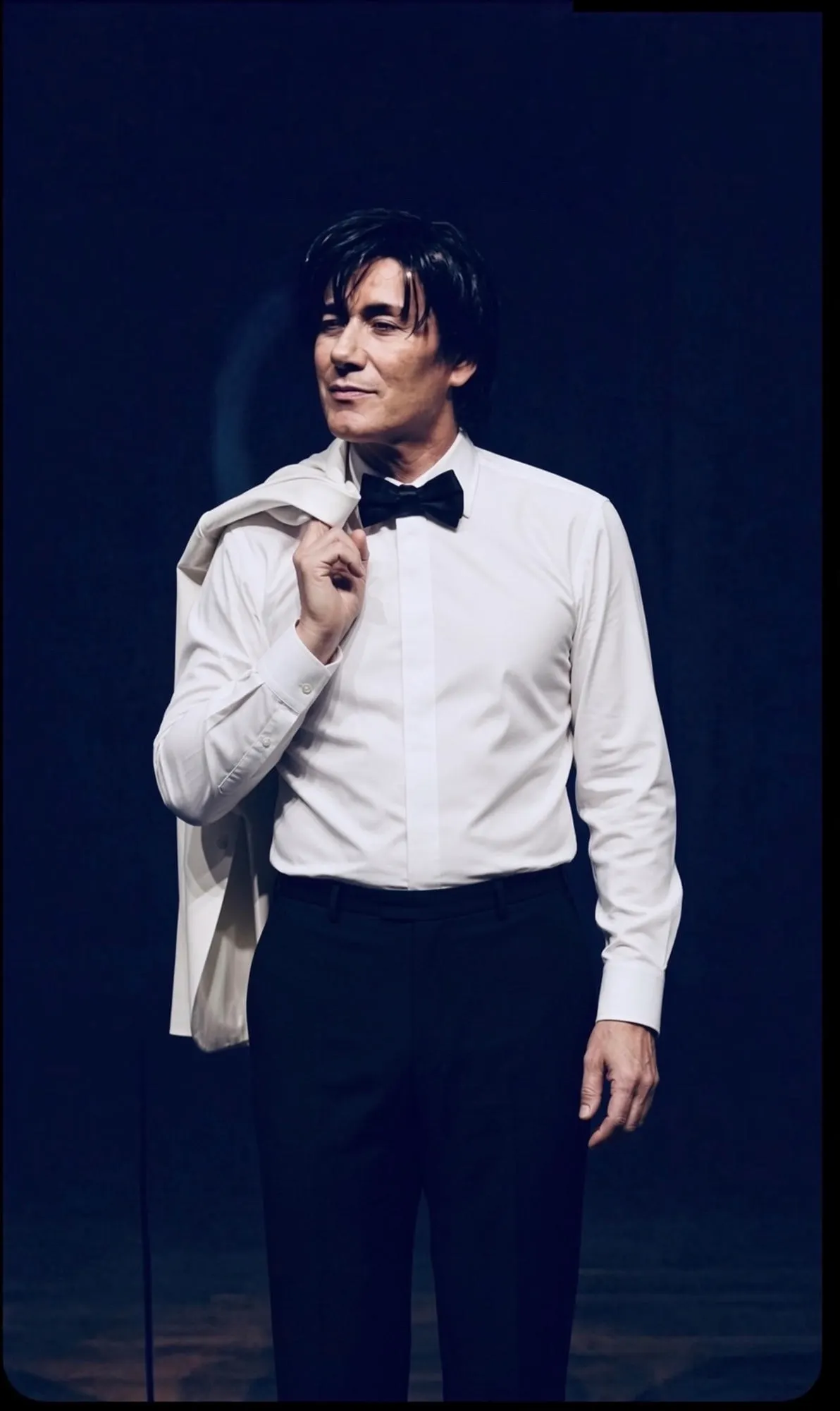Sam Stevens in a white shirt and bow tie, jacket over his shoulder